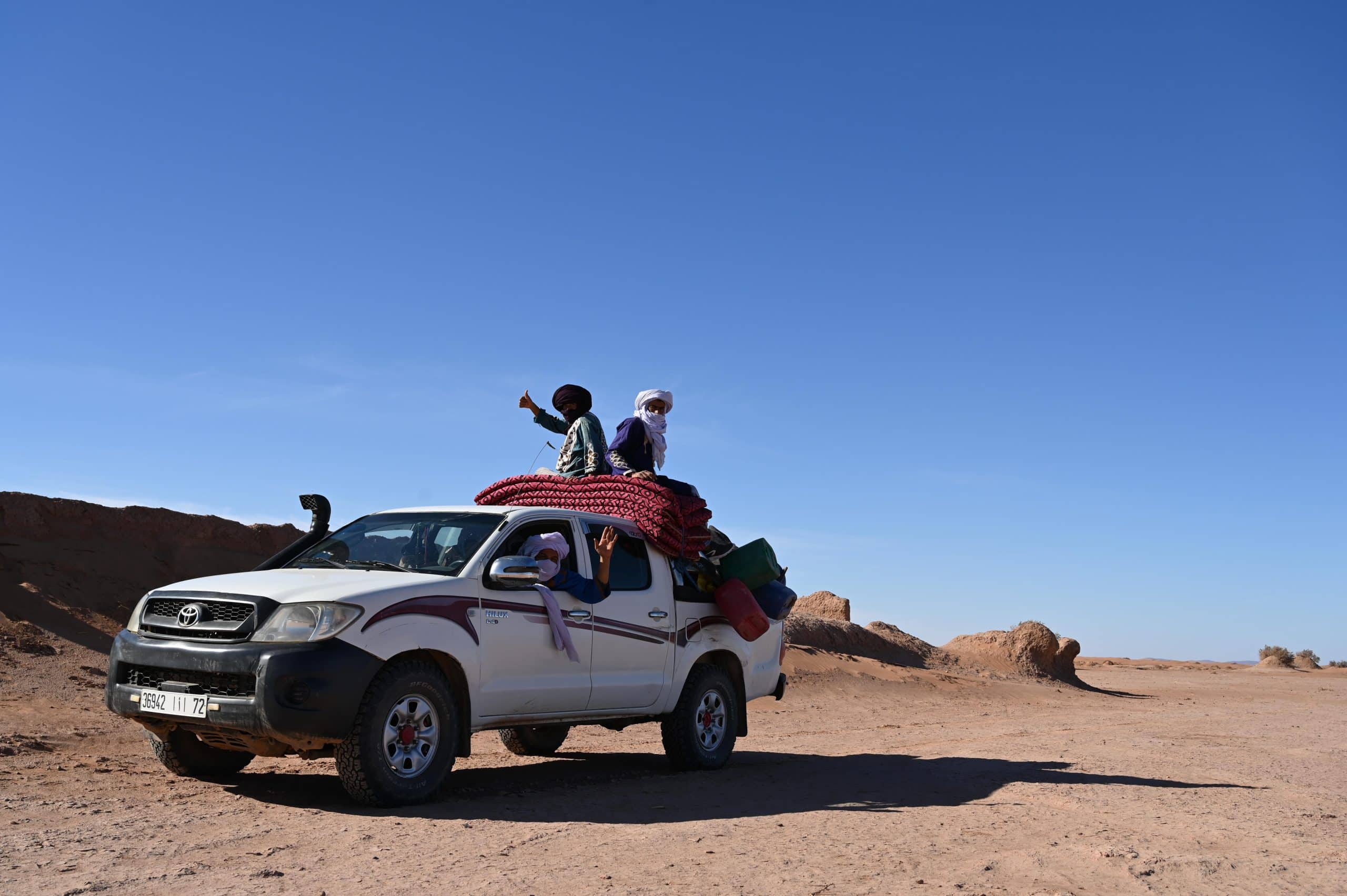Des chauffeurs et guides nomades sont dans un 4x4 dans le désert.