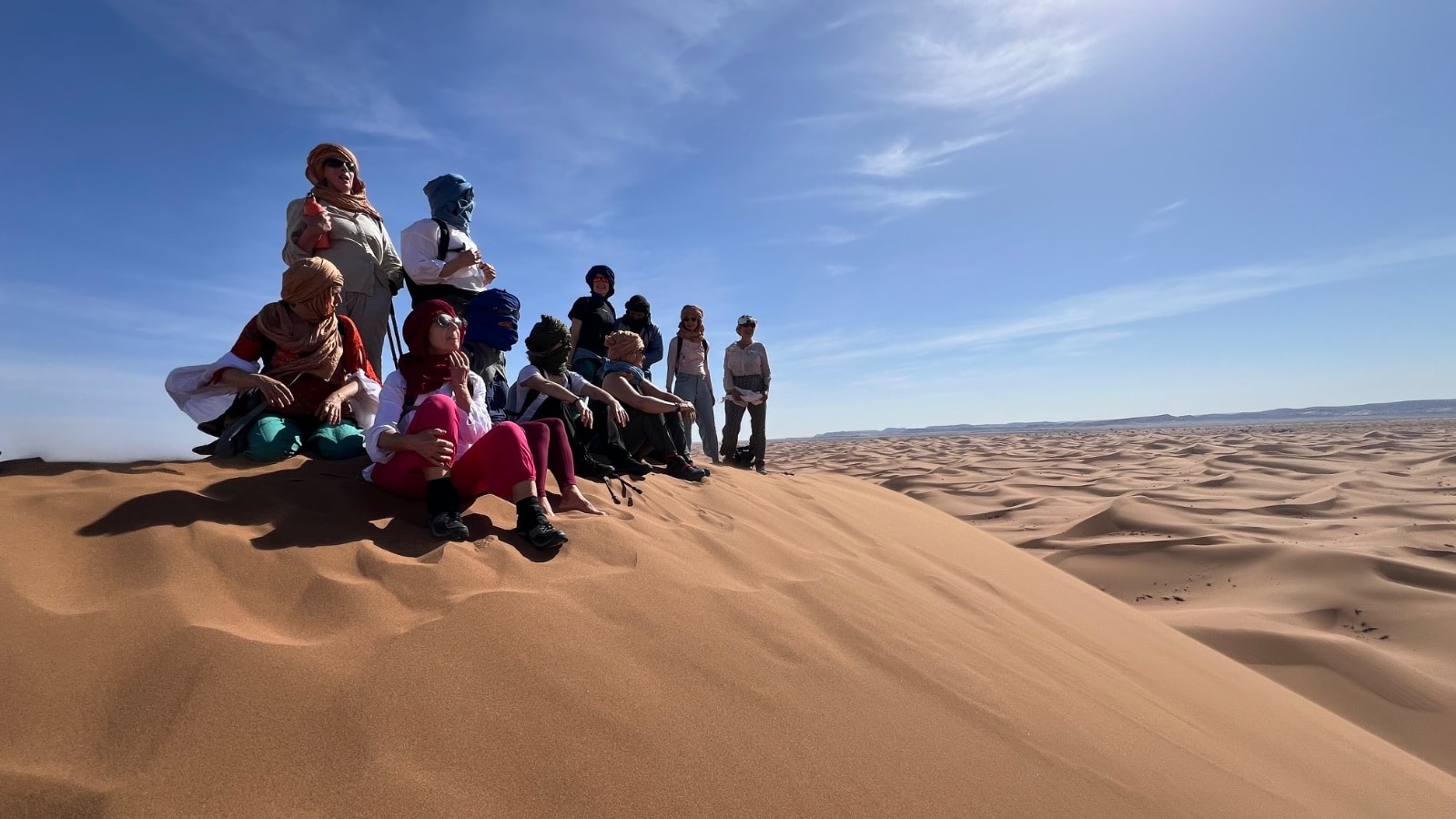 Un groupe assis sur une dune contemple le désert