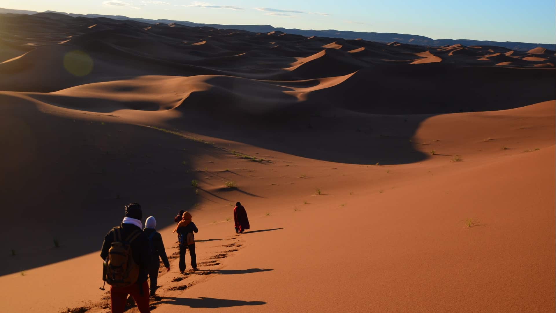 Des personnes suivent un guide dans les dunes