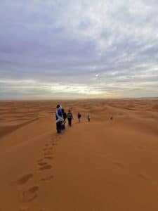 guide et trekkeurs marchent sur une piste du désert