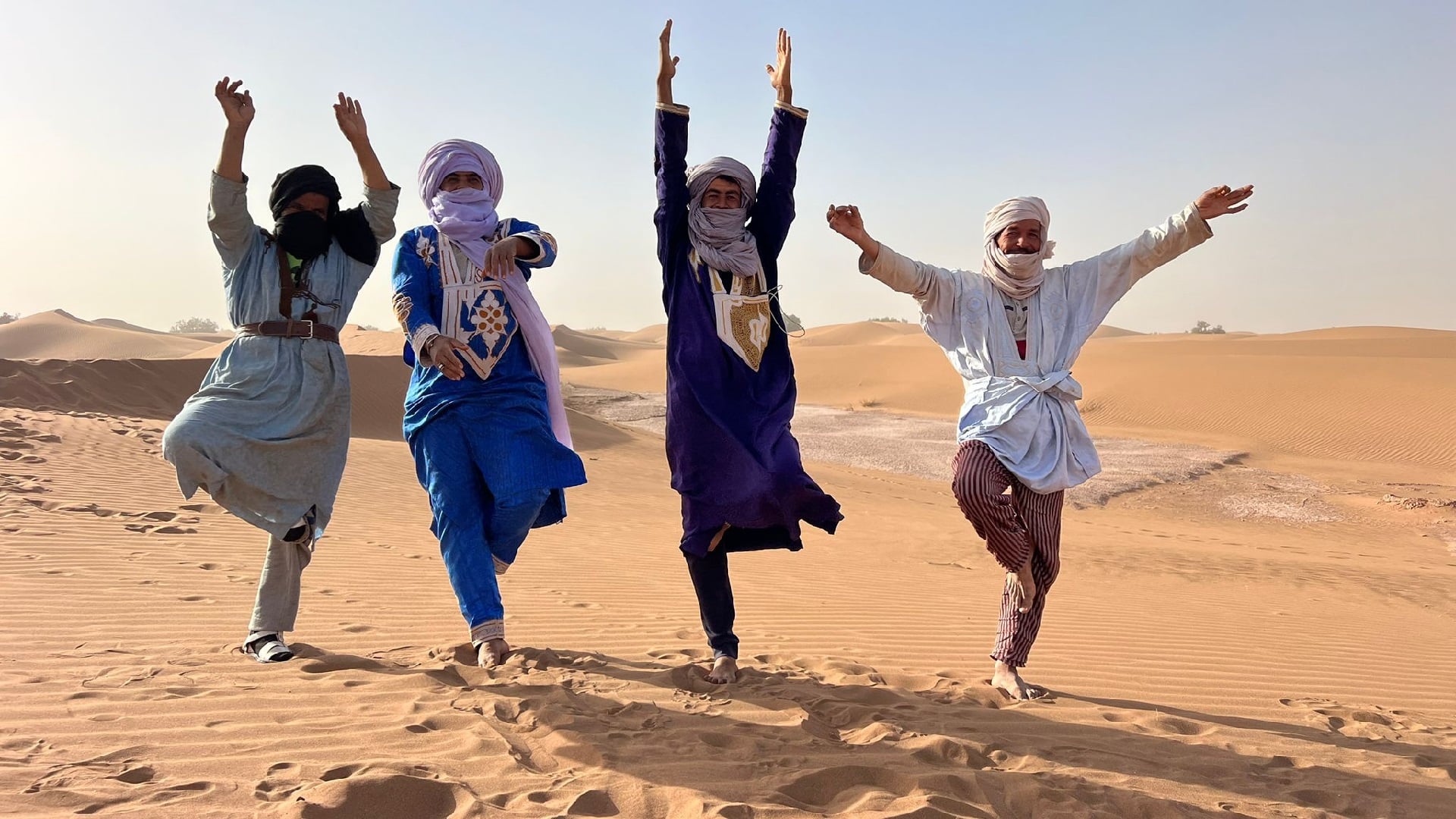 Quatre nomades s'amusent à faire des postures de Yoga dans le désert