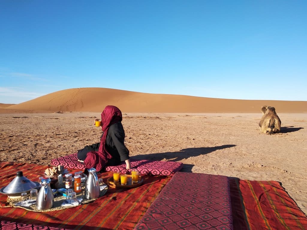 Une femme prend son petit déjeuner dans les dunes du Sahara