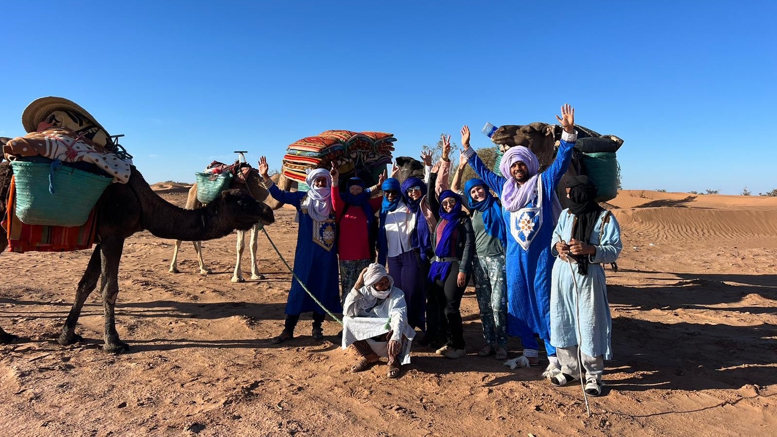 Un petit groupe de trekkeurs et nomades posent pour la photo avec les dromadaires.