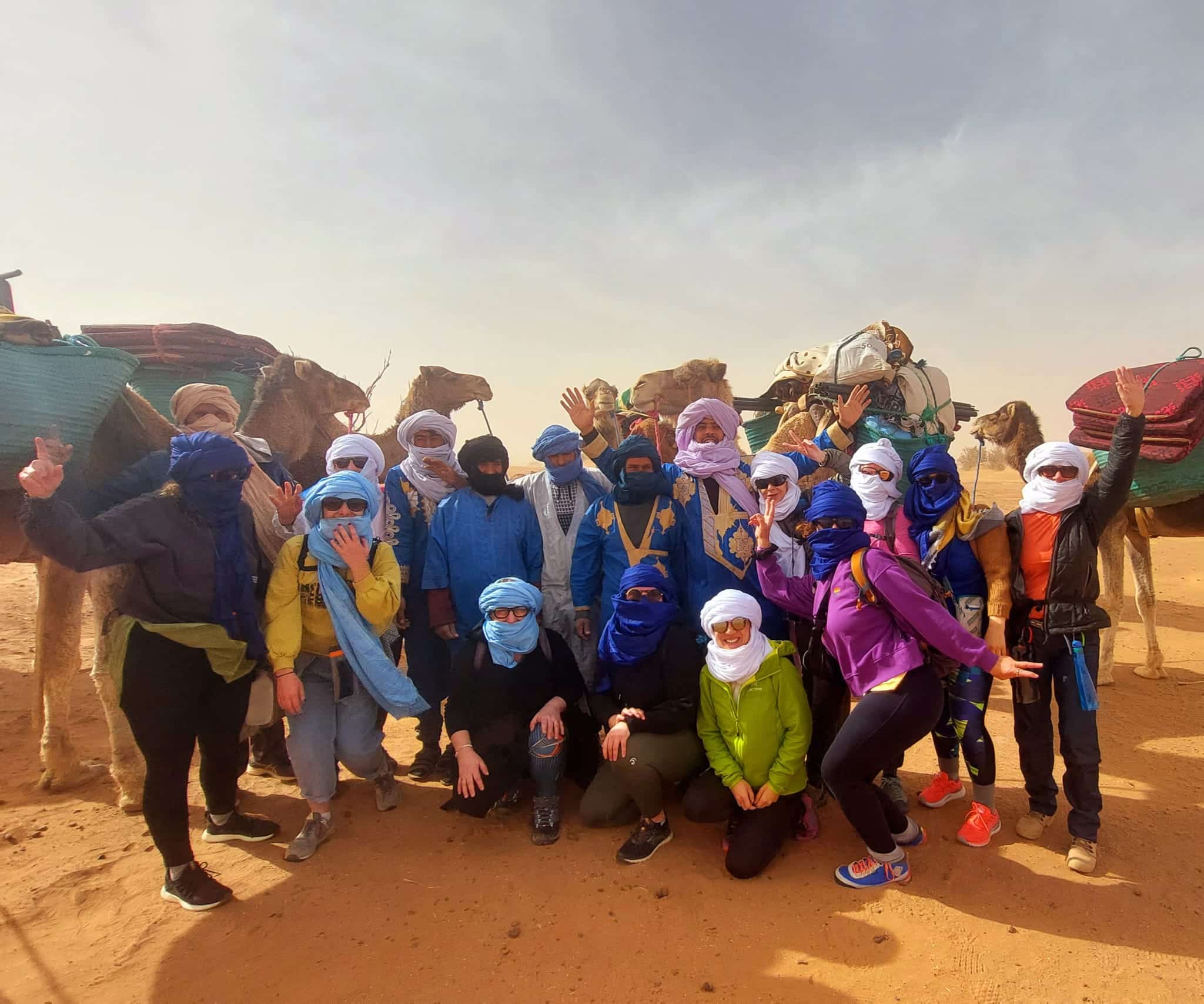 Photo de groupe avec des trekkeurs, nomades et dromadaires avant de partir dans le désert