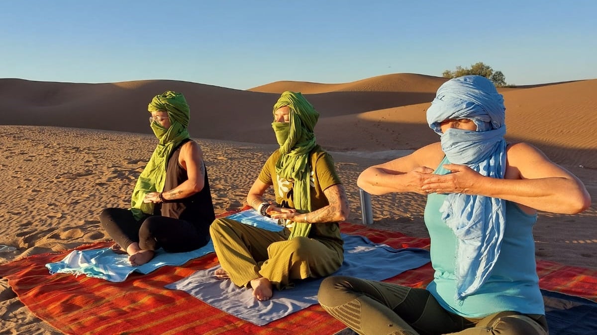 3 femmes dont des Pranayamas sur un tapis dans le désert