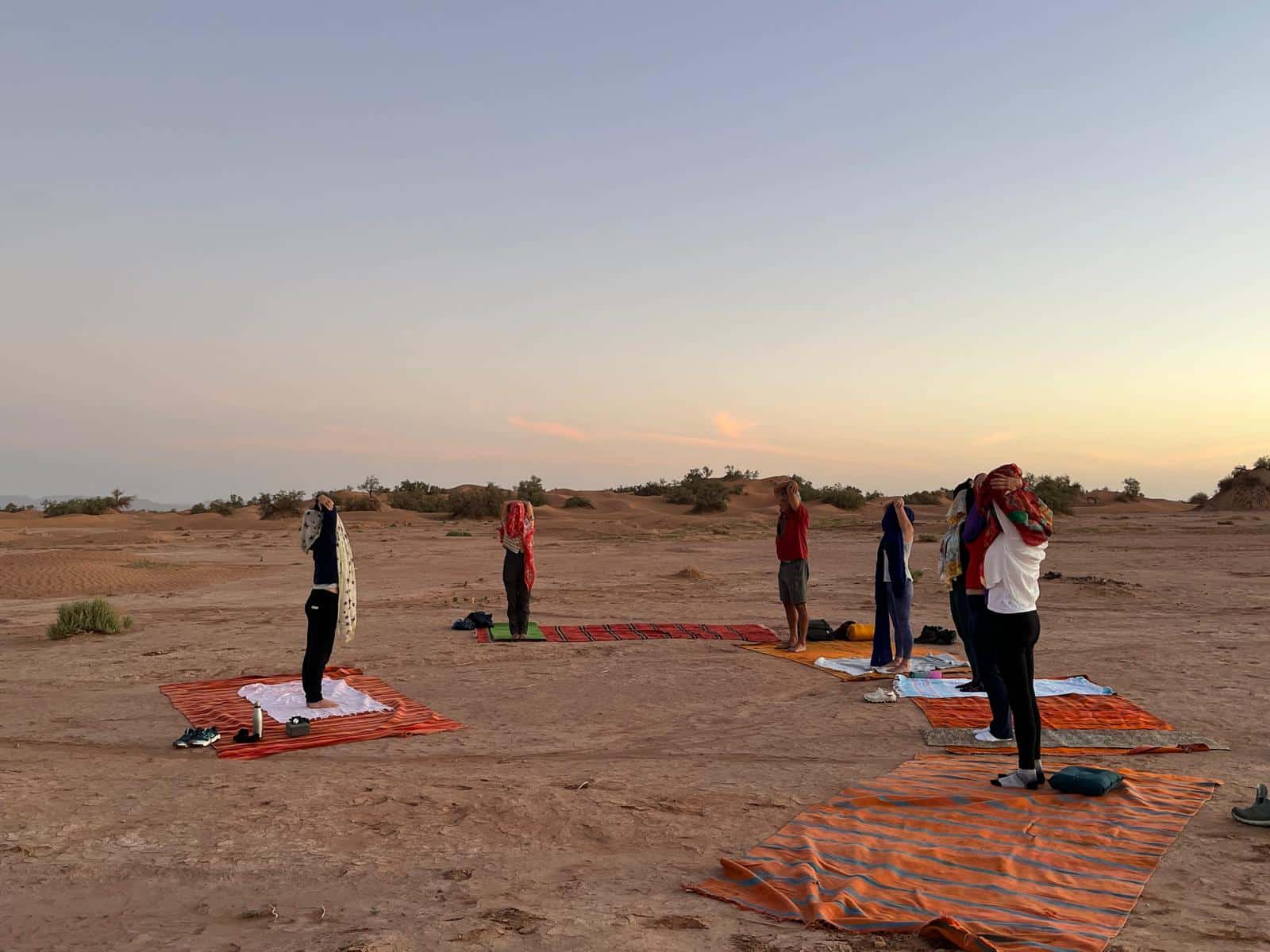 Une retraite Yoga pratique en groupe sur des tapis dans le désert