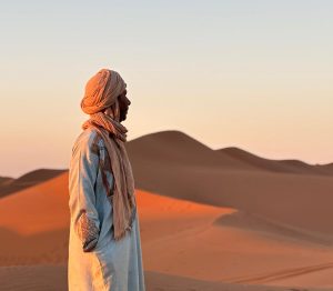 un saharaoui contemple le soleil couchant au desert